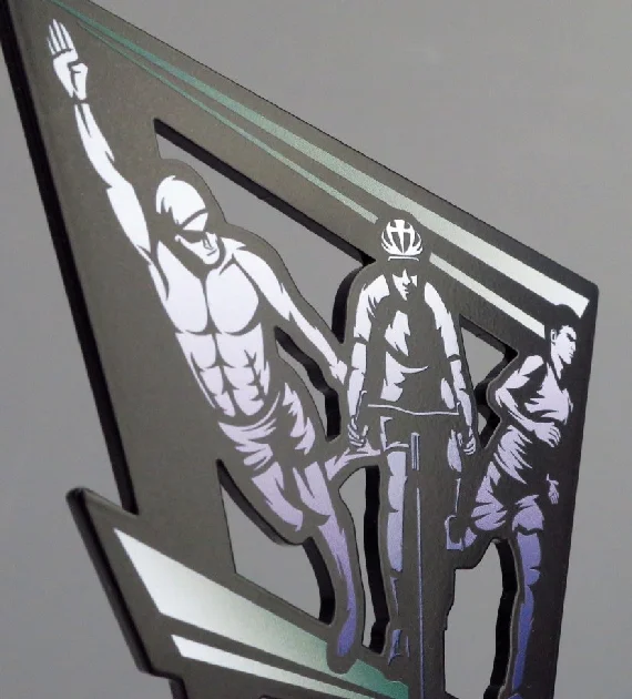 Statuetka Tri Tour wykonana z metalowego panelu wyciętego w ciekawy kształt nawiązujący do trójkąta z kolorowym nadrukiem o motywie triathlonowym - detal 1